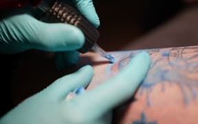 PRODUCTION - 29 November 2021, Hamburg: Tattoo artist Makowski, owner of the tattoo studio "Älteste Tätowierstube in Deutschland" in the St. Pauli district, tattoos a customer with colorful tattoo ink. In January, a ban on colorful tattoo ink comes into effect in the EU. (to dpa-Korr "Only doom and gloom? EU regulation threatens colorful tattoo colors") Photo: Marcus Brandt/dpa (Photo by MARCUS BRANDT / DPA / dpa Picture-Alliance via AFP)