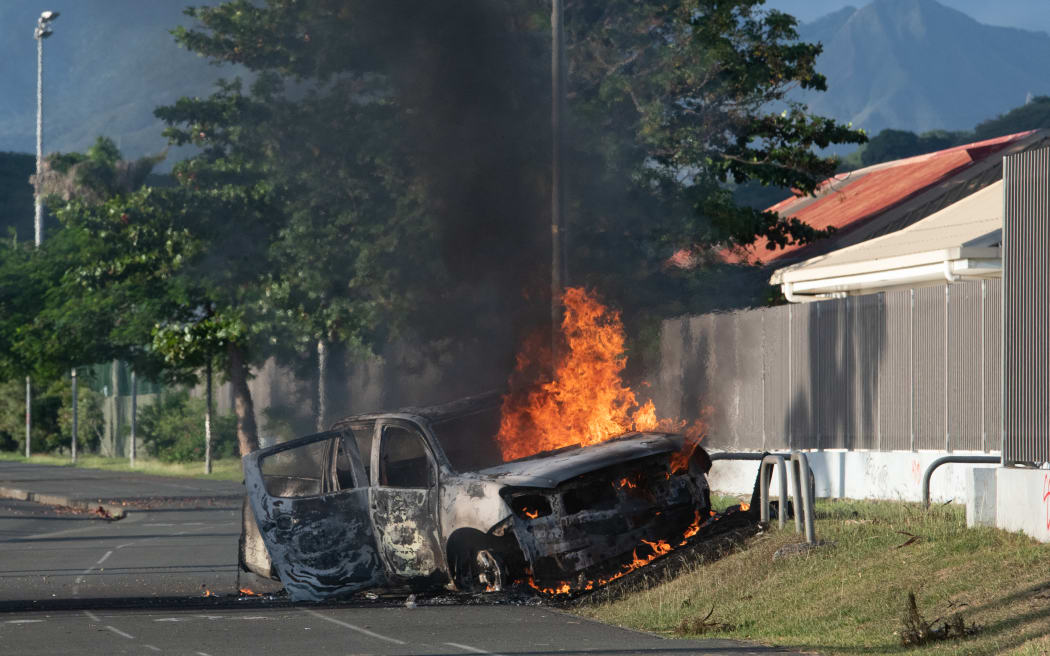 A car is burning on the Normandie provincial road, outside Noumea on May 16, 2024, amid protests linked to a debate on a constitutional bill aimed at enlarging the electorate for upcoming elections of the overseas French territory of New Caledonia.