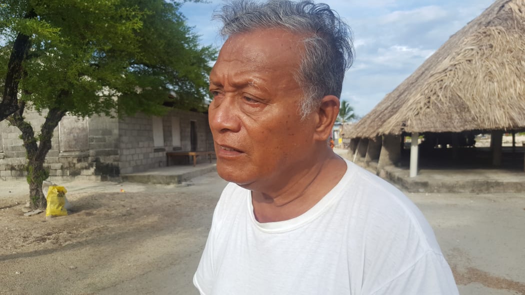 Pastor stands in front of thatched traditional village meeting hall