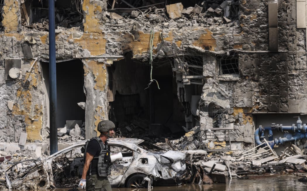 A member of the security forces walks past an Israeli police station in Sderot after it was damaged during battles to dislodge Hamas militants who were stationed inside, on October 8, 2023. Israel's prime minister of October 8 warned of a "long and difficult" war, as fighting with Hamas left hundreds killed on both sides after a surprise attack on Israel by the Palestinian militant group. (Photo by RONALDO SCHEMIDT / AFP)