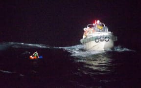 A man in the water with a rescue boat nearby.