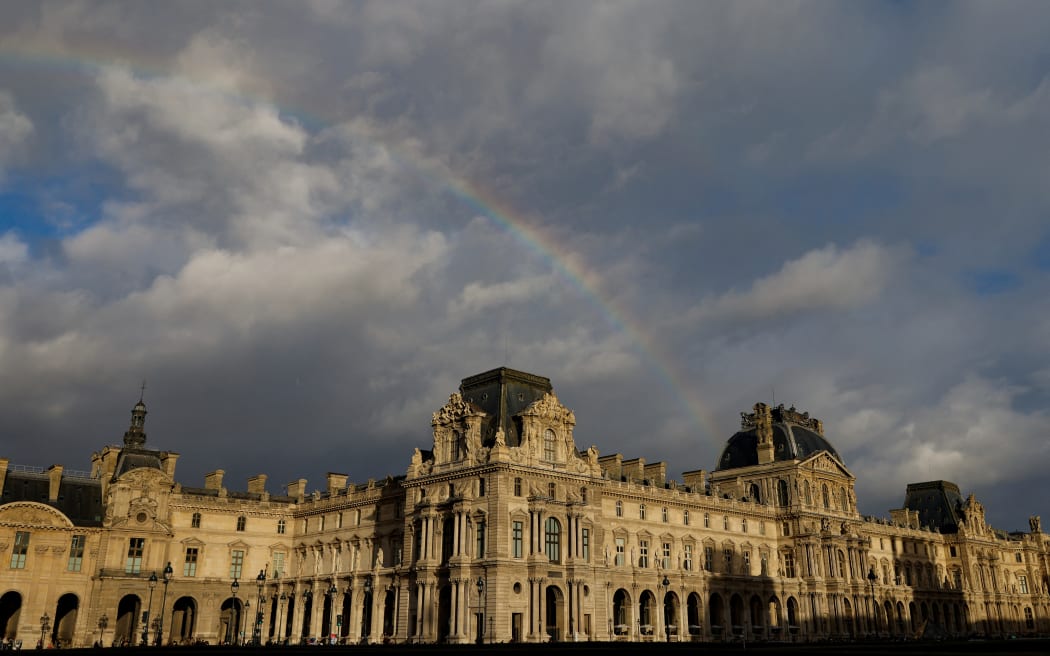 (FILES) A rainbow emerges over the Louvre museum, bathed in late afternoon sunlight, in Paris, on December 6, 2025. A water leak on November 26, 2025 damaged several hundred items in the Louvre's Egyptian Antiquities library, the Paris museum told AFP on December 7, 2025, confirming a report by La Tribune de l'Art. (Photo by Ian LANGSDON / AFP)