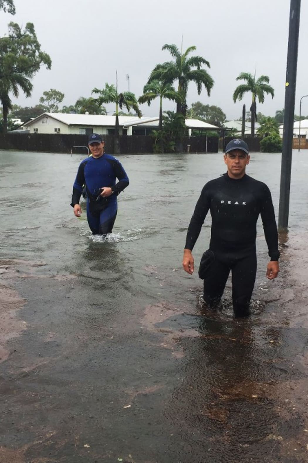 A handout picture provided by Queensland Police Service, taken on February 2, 2019 and release on February 3 shows two police officers wading in flood waters in Townsville. -