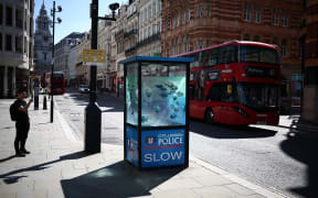 People photograph an artwork by street artist Banksy, the seventh to released this week, depicting fish swimming around a Police Box, in the City of London, on August 11, 2024. The artist confirmed the work to be theirs after posting an image of it on the social media app Instagram. (Photo by HENRY NICHOLLS / AFP) / RESTRICTED TO EDITORIAL USE - MANDATORY MENTION OF THE ARTIST UPON PUBLICATION - TO ILLUSTRATE THE EVENT AS SPECIFIED IN THE CAPTION