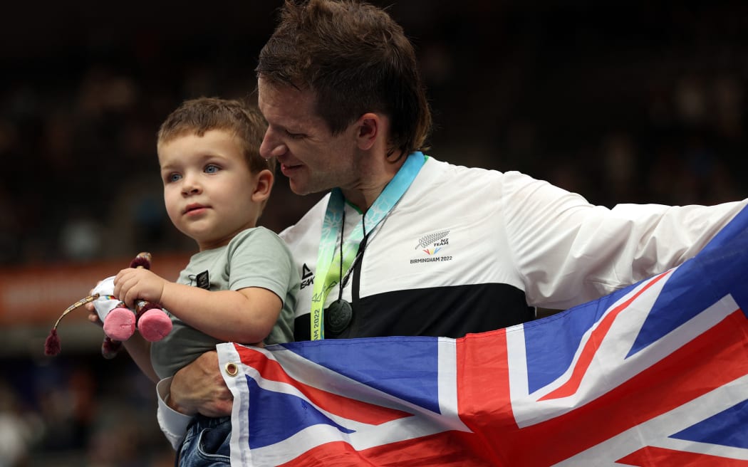 Gold medallist Aaron Gate holds son Axel as he celebrates during the medal presentation ceremony for the men's 1000m time trial cycling event at the Commonwealth Games on 1 August 2022.