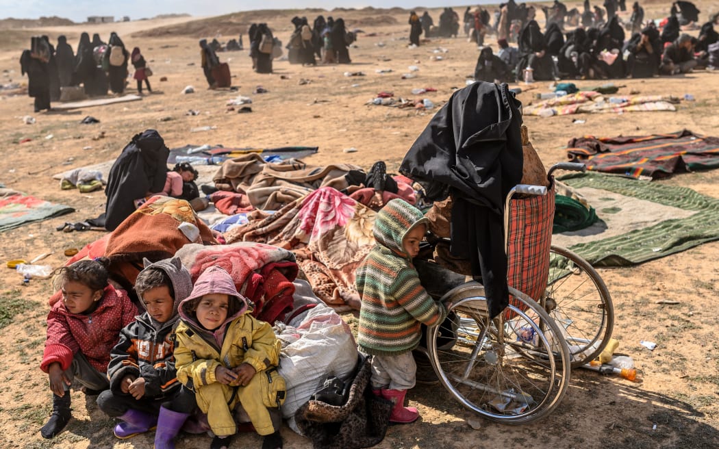 An injured woman and her four children evacuated from the Islamic State (IS) group's embattled holdout of Baghouz sit at a screening area held by the US-backed Kurdish-led Syrian Democratic Forces (SDF)