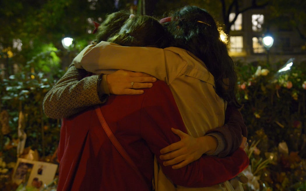 People hug in front of a memorial set up near the Bataclan theatre in Paris.
