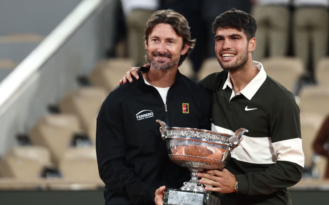 (FILES) Spain's Carlos Alcaraz poses with his Spanish coach Juan Carlos Ferrero (L) after winning against Italy's Jannik Sinner at the end of their men's singles final match on day 15 of the French Open tennis tournament on Court Philippe-Chatrier at the Roland-Garros Complex in Paris on June 8, 2025. Men's tennis world number one Carlos Alcaraz announced on December 17, 2025 on social media he is splitting from his coach Juan Carlos Ferrero after seven hugely successful years. (Photo by Thibaud MORITZ / AFP)