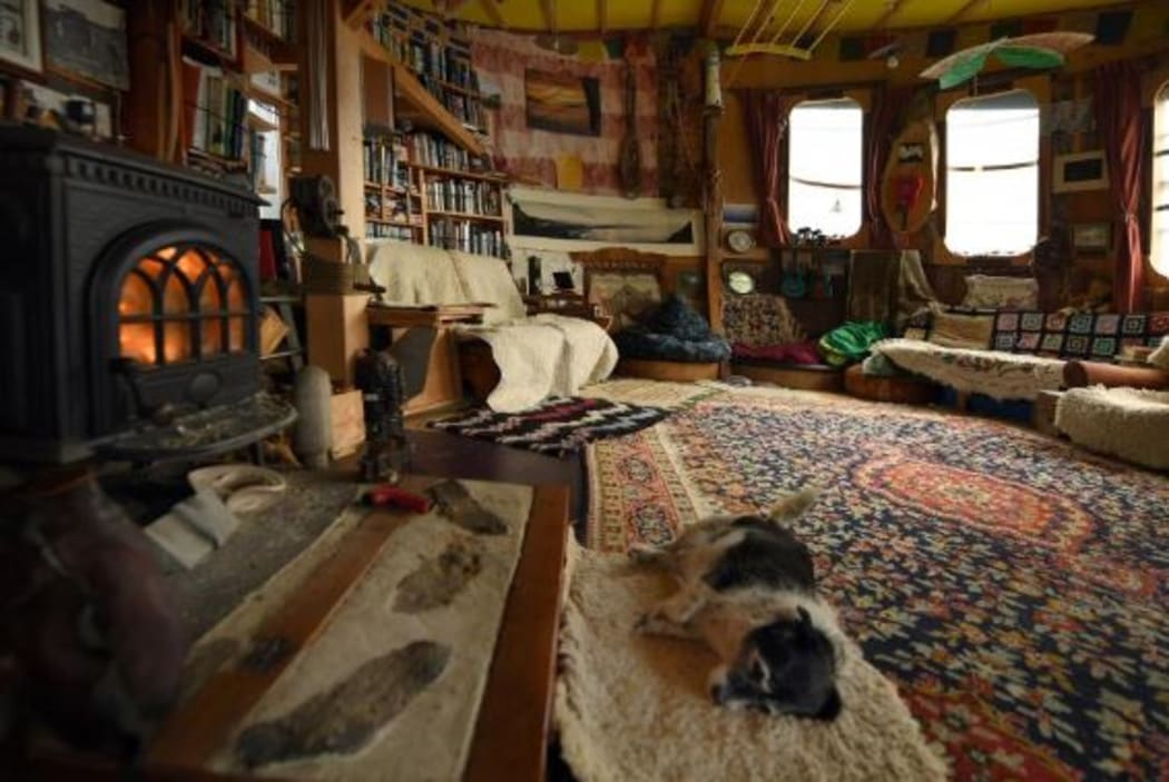 Olive the dog rests in front of the fire inside Aramoana man Just Doi's structure which he says is a boat.