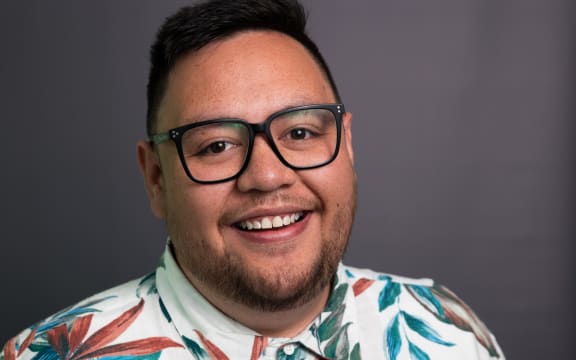 Corey Fuimaono smiling in front of grey background