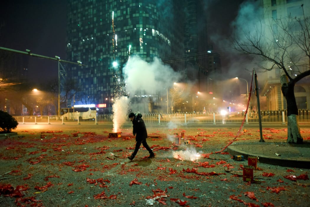 A man walks among firework papers in the streets of Beijing on 28 January, 2017, just after midnight marking the start of the Lunar New Year.