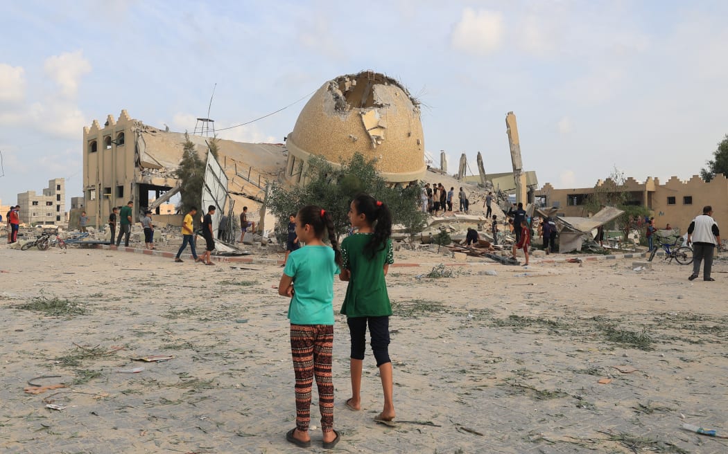 Two Palestinian girls stand in front of a mosque destroyed in Israeli airstrikes in Khan Yunis in the southern Gaza Strip, on October 8, 2023. Fighting between Israeli forces and the Palestinian militant group Hamas raged on October 8, with hundreds killed on both sides after a surprise attack on Israel prompted Prime Minister Benjamin Netanyahu to warn they were "embarking on a long and difficult war". (Photo by SAID KHATIB / AFP)