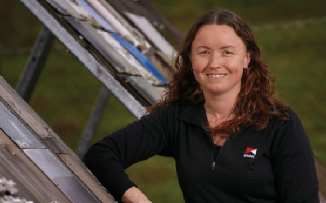 Katy Stokes leans against a stack of construction materials