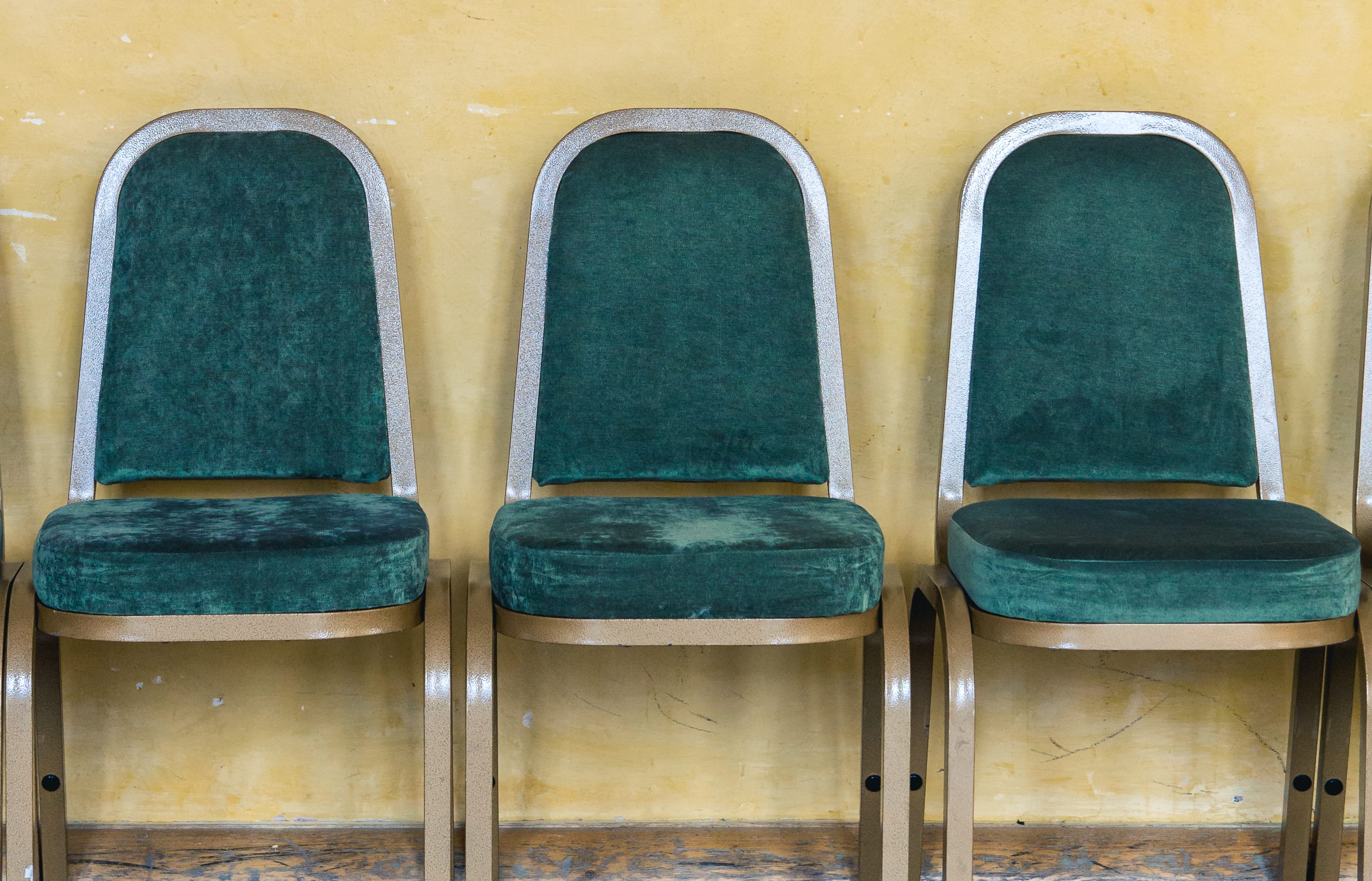Green chairs lined up against a yellow wall in a waiting area