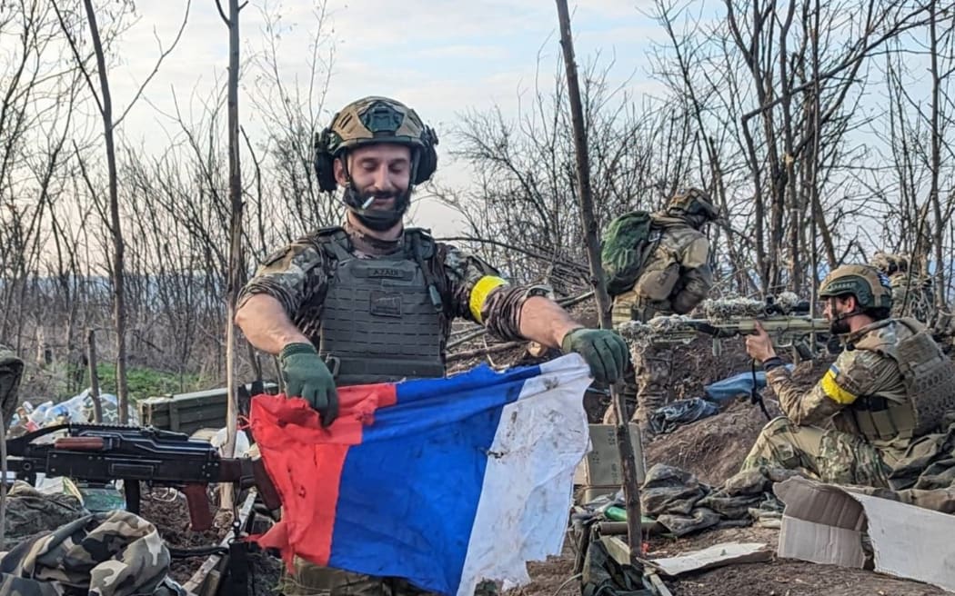 A soldier holds remnants of a Russian flag.