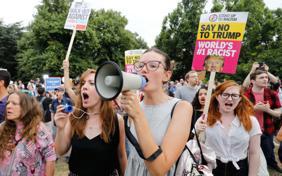Protesters against the visit of US President Donald Trump gather with placards at a barrier set up to block access to the US ambassador's residence Winfield House in Regents Park in London.