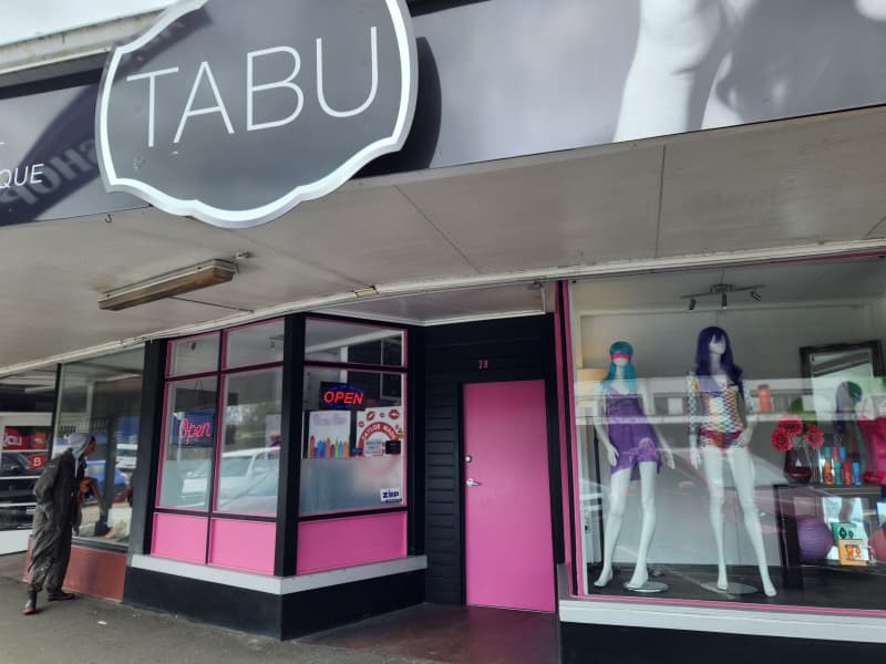 The closed pink door and shop windows on the main street running through Eketāhuna, with Tabu shop sign above
