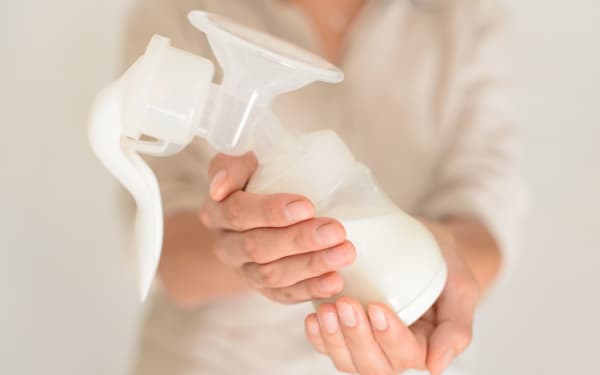 Mother holds breast pump in her hand, blurred background
