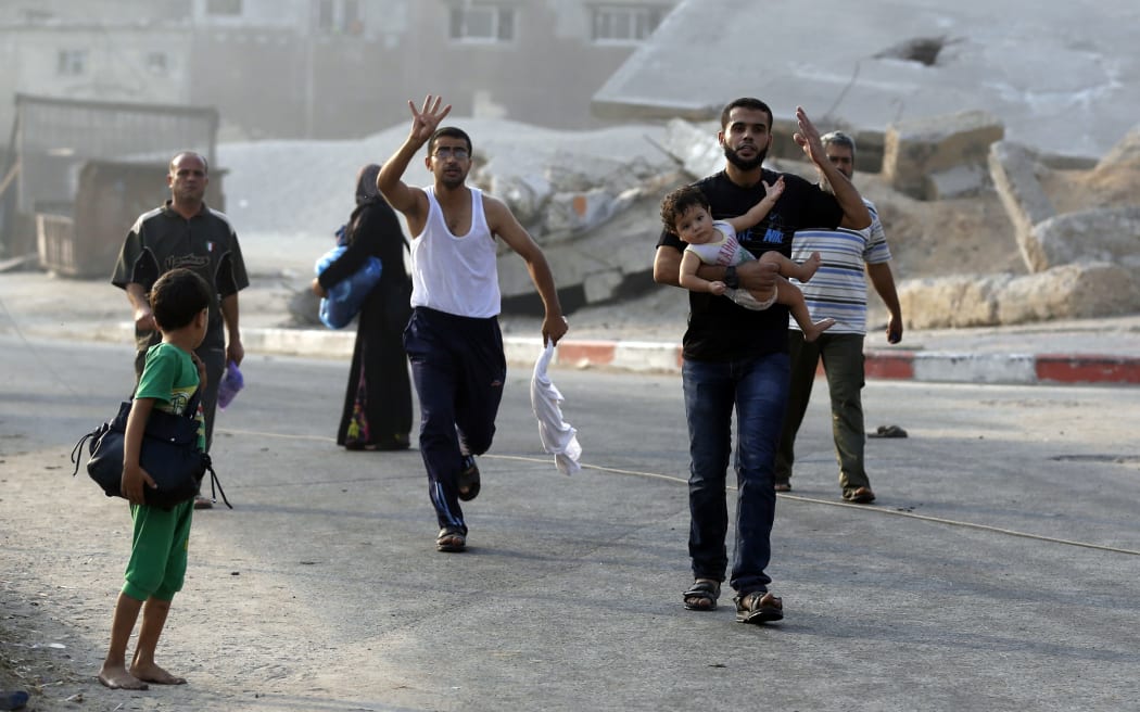Palestinians fleeing their homes in Gaza's eastern Shejaiya district after heavy Israeli shelling left casualties lying in the streets.