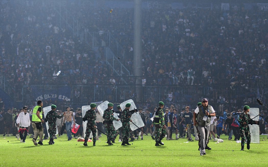 This picture taken on October 1, 2022 shows members of the Indonesian army securing the pitch after a football match between Arema FC and Persebaya Surabaya at Kanjuruhan stadium in Malang, East Java. - At least 127 people died at a football stadium in Indonesia late on October 1 when fans invaded the pitch and police responded with tear gas, triggering a stampede, officials said. (Photo by AFP)