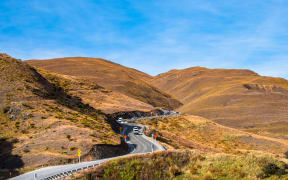 The beautiful Crown Range Road between Queenstown and Wanaka via Crown range. Grassland and beautiful landscape of rocky mountains.