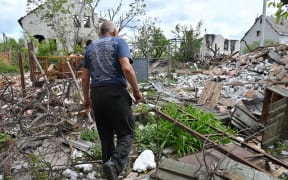 A local resident walks among debris in a yard of his destroyed house in the village of Mala Rogan, east of Kharkiv, on May 15, 2022, amid Russian invasion of Ukraine.