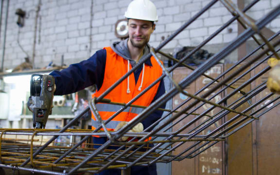 A factory worker attaches steel mesh at a concrete reinforcement factory.