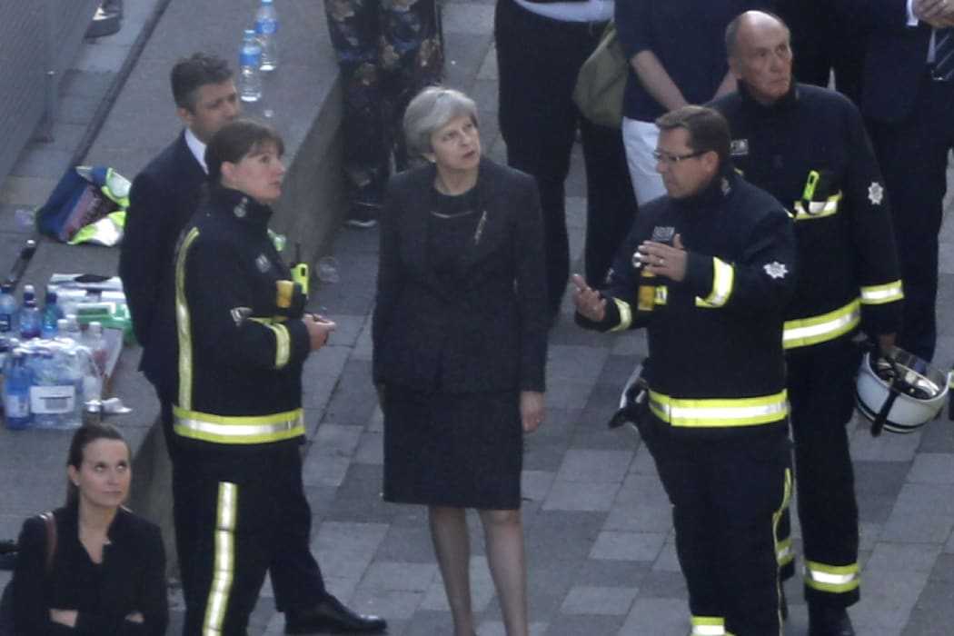 British Prime Minister Theresa May meeets firefighters as she visits the remains of Grenfell Tower.