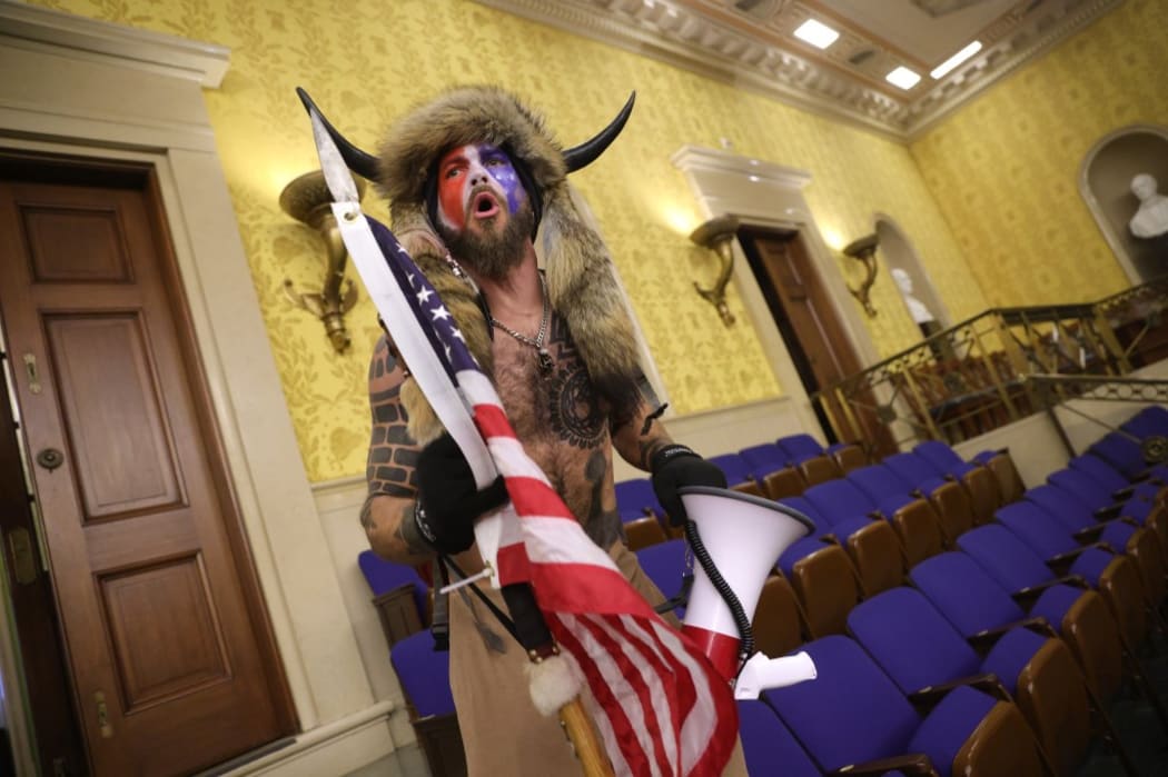 Jacob Anthony Chansley is alleged to be the man seen wearing horns and a fur hat in photographs, including this from inside the Senate chamber.