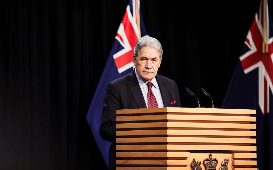 Winston Peters standing in the Beehive Theatre, making an announcement.