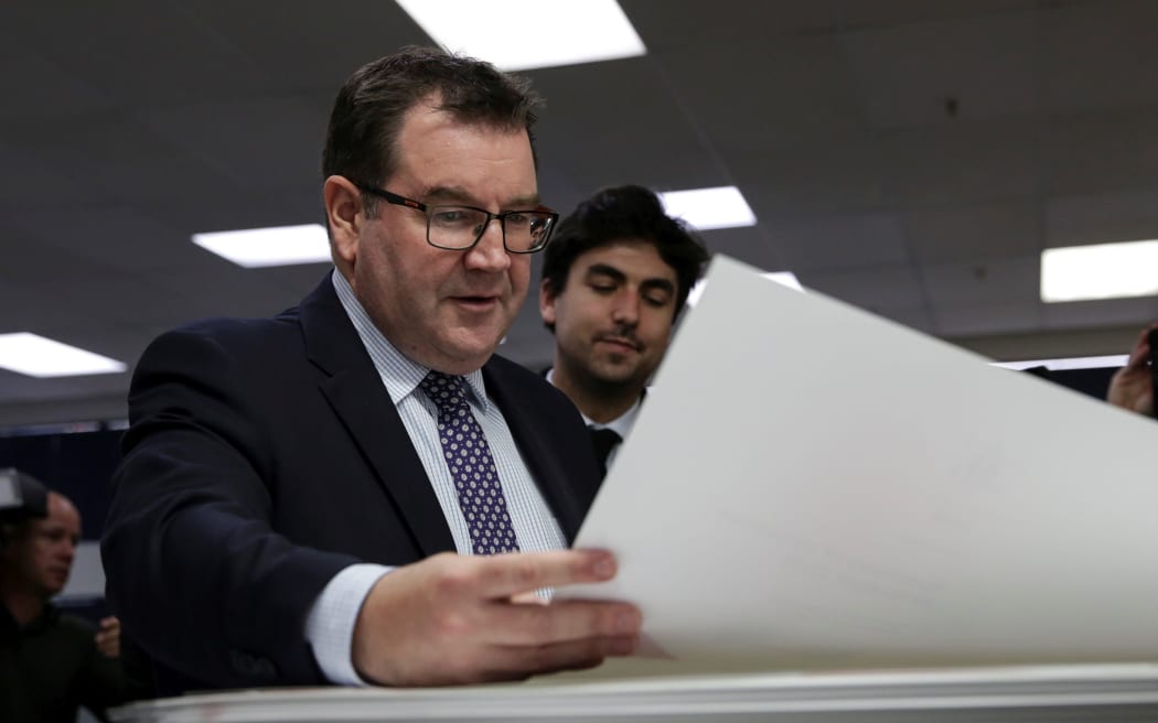 Grant Robertson looking over the first print of his first budget.