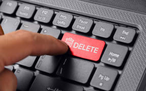 Gesture of a hand finger pressing DELETE on a laptop keyboard