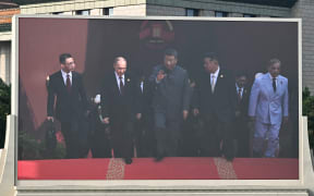A display shows China's President Xi Jinping (C) walking alongside Russia's President Vladimir Putin (centre L) and North Korea's leader Kim Jong Un (centre R) before a military parade marking the 80th anniversary of victory over Japan and the end of World War II, in Beijing’s Tiananmen Square on September 3, 2025. (Photo by Pedro Pardo / AFP)