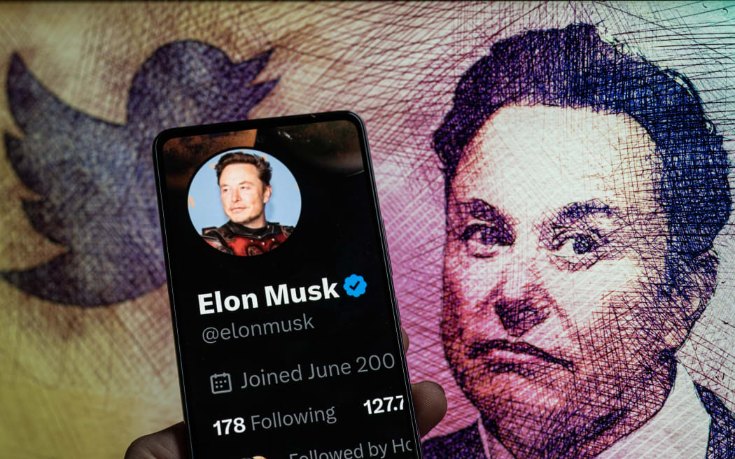 Elon Musk Twitter account seen on Mobile with Elon Musk in the background seen in this photo illustration.