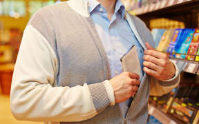 Shoplifter stealing bar of chocolate in a supermarket.