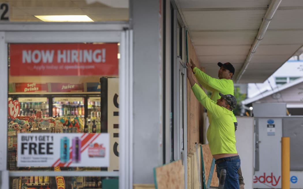 Workers place plywood over the windows of a business before the arrival of Hurricane Helene, on 25 September, 2024, in Clearwater, Florida.
