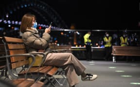 A woman waits for a ferry at Circular Quay near Sydney Harbour Bridge during lockdown in Sydney yesterday.