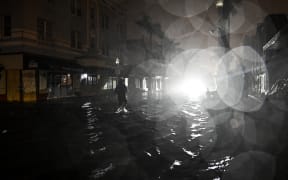 A man walks through water-flooded streets after Hurricane Milton made landfall in Fort Myers, Florida, on October 9, 2024. - Milton made landfall in Florida October 9, 2024 as an "extremely dangerous" Category 3 hurricane, packing life-threatening storm surge, extreme winds and flash flooding, the National Hurricane Center (NHC) said. "Data indicate the eye of Hurricane Milton has made landfall near Siesta Key in Sarasota County along the west coast of Florida," the NHC said in an 8:30 pm (0030 GMT Thursday) bulletin. (Photo by CHANDAN KHANNA / AFP)