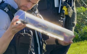 An officer holds the machete after putting it inside a case.