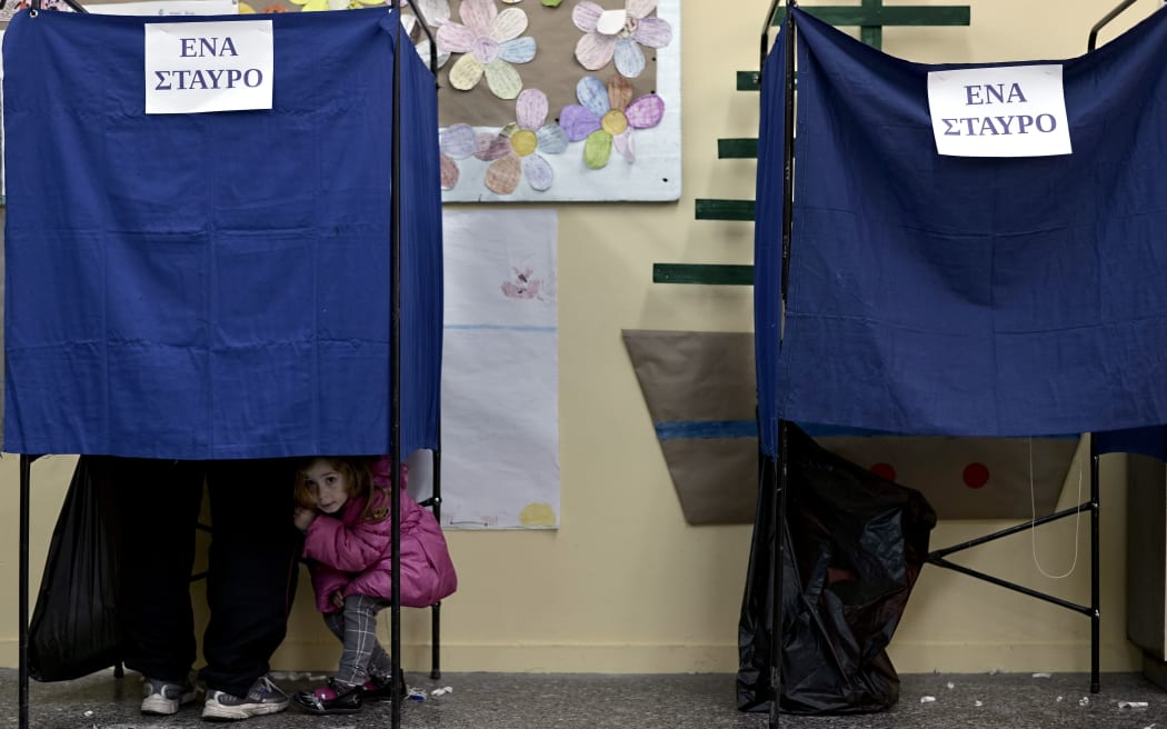 A girl looks out a voting booth at a polling station in Athens in January 2015.
