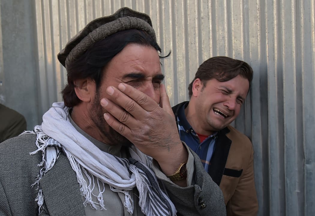 Two Afghan men weep for their relatives after gunmen dressed as doctors killed more than 30 people at a Kabul hospital.