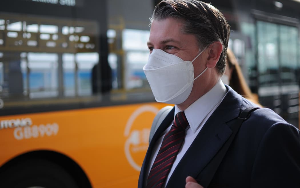 Minister of Transport Michael Wood waiting to catch an AirportLink bus to Puhinui Station Interchange on Friday.