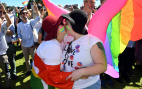 A couple embrace as supporters of the same-sex marriage "Yes" vote celebrate the announcement in a Sydney park.