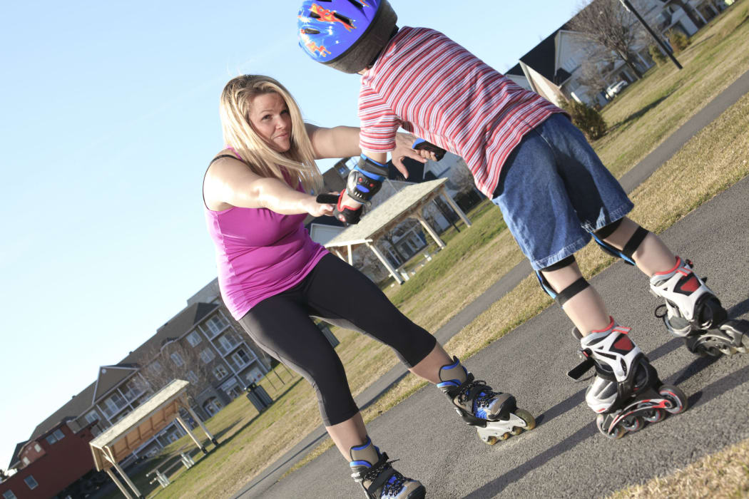 A photo of a mother teaching her son to roller blade.