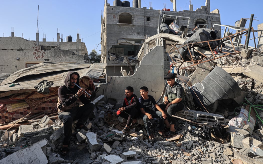 A man entertains children amid the ruins of the family home destroyed in an Israeli strike in Rafah in the southern Gaza Strip, on 7 November 2023.