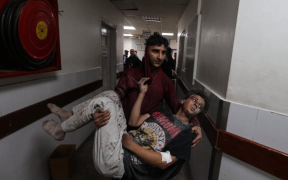 A man carries a Palestinian youth injured in Israeli bombardment, at the al-Najjar hospital in Rafah in the southern Gaza Strip on March 24, 2024, amid the ongoing conflict between Israel and the militant group Hamas.