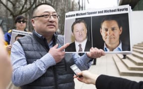 Louis Huang of Vancouver Freedom and Democracy for China holds photos of Canadians Michael Spavor and Michael Kovrig, who are being detained by China, outside British Columbia Supreme Court, in Vancouver, on March 6, 2019,