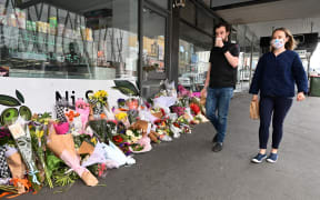 People walk past a floral tribute to a popular Melbourne delicatessen owner who died from Covid-19, 11 October 2021.