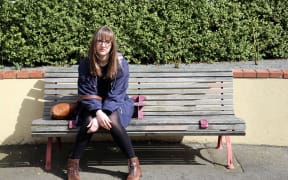 A photo of Louise Burston looking pensive on a park bench
