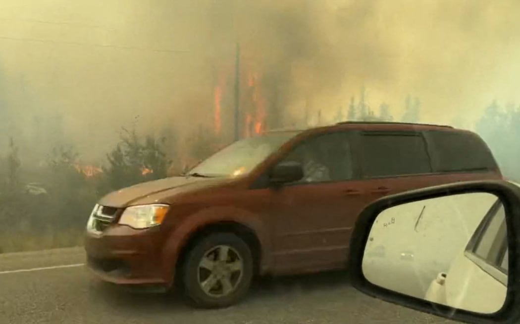 This screengrab from a video provided by Jordan Straker shows vehicles driving on the freeway as people evacuate from Yellowkife, Northwest Territories, Canada, on August 16, 2023. Thousands ordered to flee wildfires advancing on one of the largest cities in Canada's far north crammed into a local airport on August 17, 2023, to board emergency evacuation flights, as convoys snaked south to safety on the only open highway.